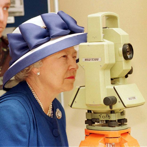 Queen Elizabeth II looking though a Theodolite